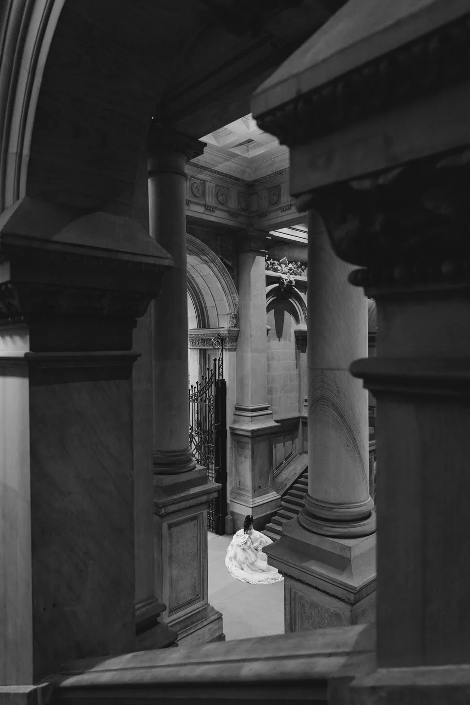 Black and white photo of Celeste in her gown, seen from afar between stone columns.